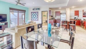 Un salon moderne avec une table à manger en verre, un canapé et un ventilateur de plafond.