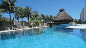 A clear blue pool with lounge chairs and palm trees. - Family Suite | 2BR, 2 Bath, Pool & 24h Security (Cancún)