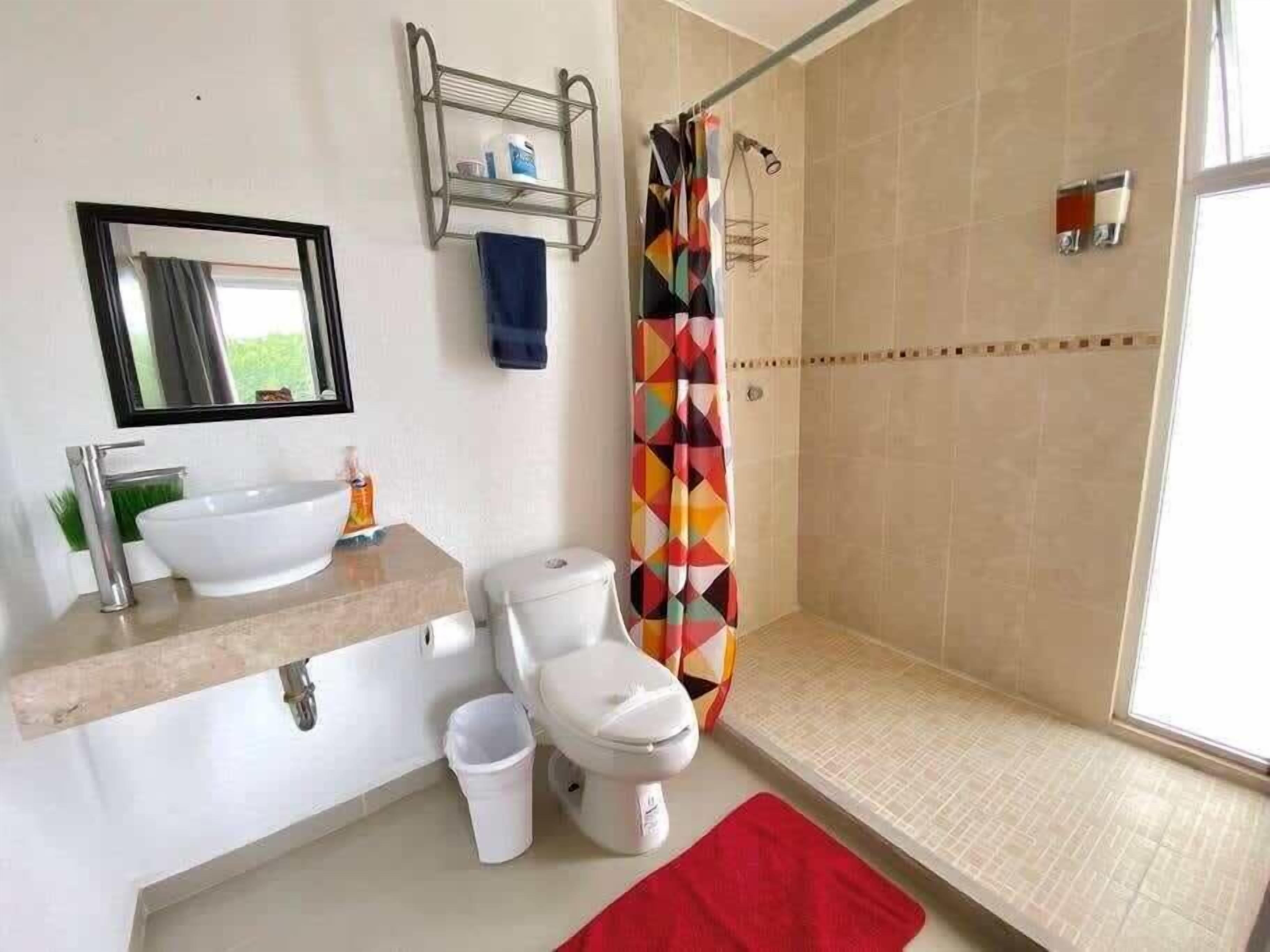Un baño con lavamanos, inodoro, ducha y espejo.