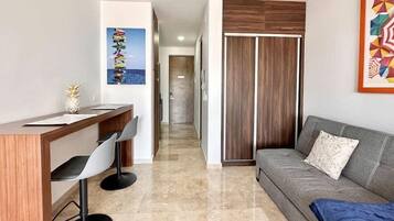 A modern living room with a sofa, a dining area with a table and chairs, a wooden cabinet, and a hallway leading to another room.