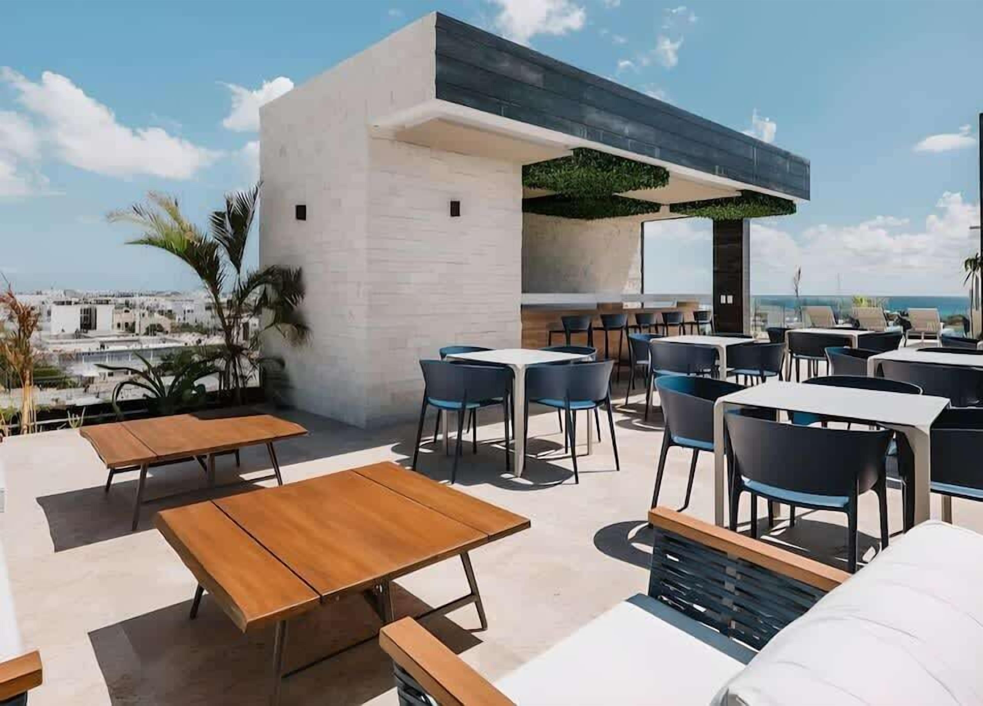 Un espace extérieur aménagé avec des tables et des chaises, une structure de bâtiment moderne et une vue sur le paysage urbain.