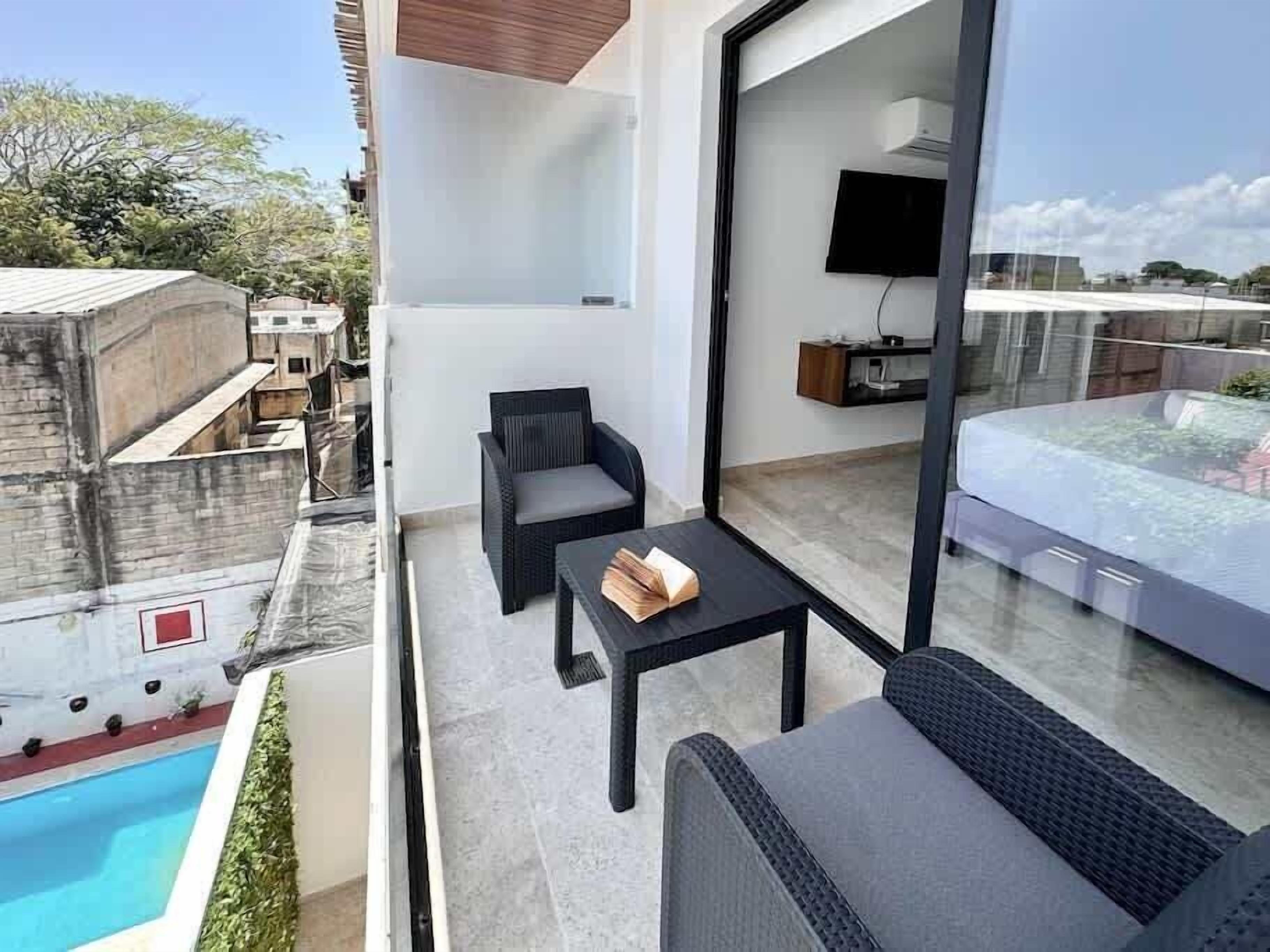 Un balcon avec une piscine, un canapé, une table et un téléviseur.