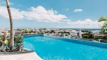 A swimming pool with a view of a coastal town and palm trees.