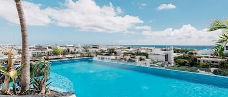Piscina com vista para uma cidade costeira e palmeiras.