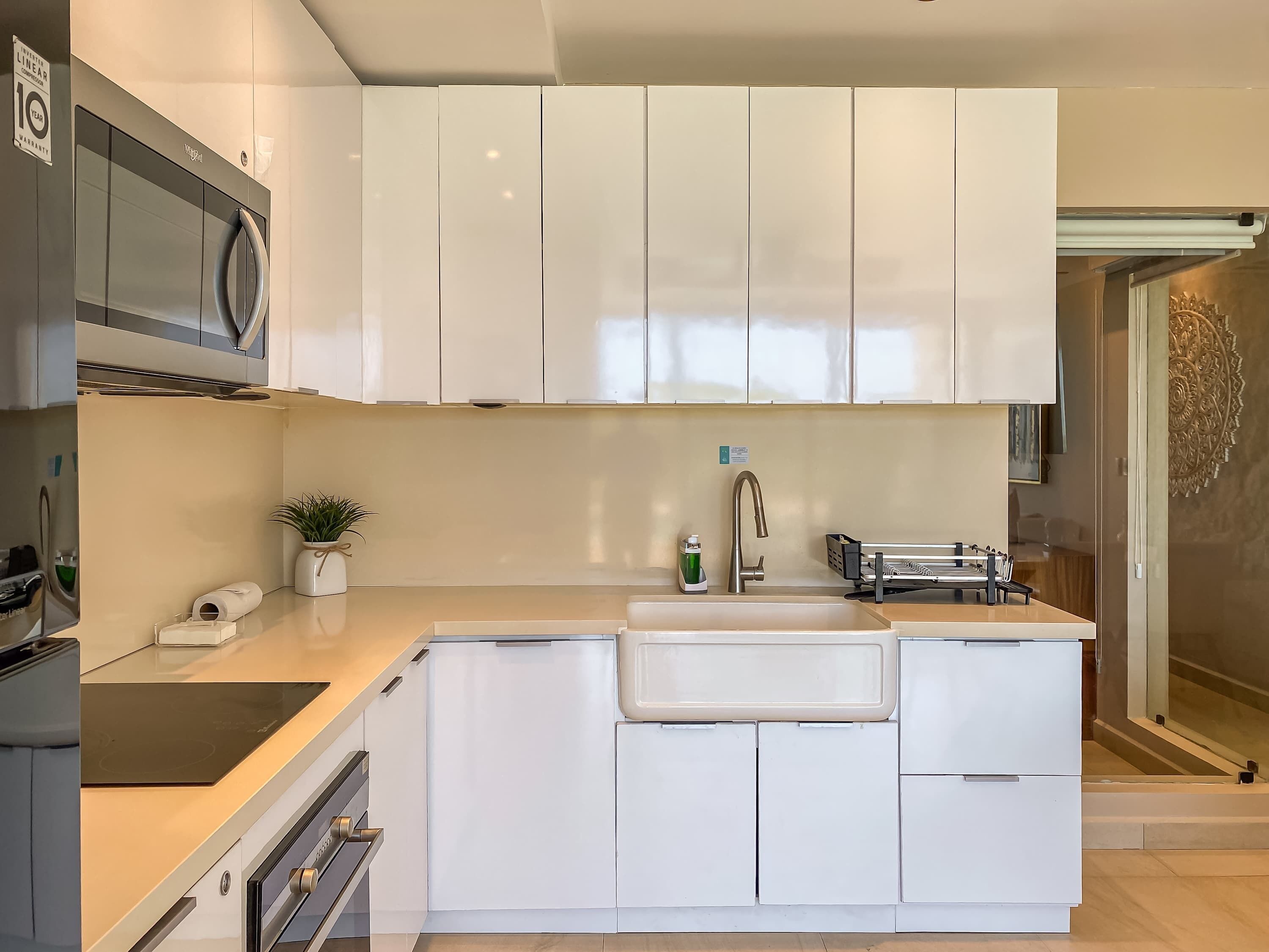 A compact kitchen with white cabinets, a built-in microwave, and a sink.