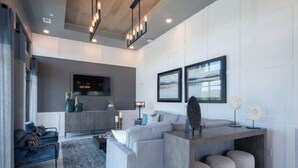 Una sala de estar moderna con un sofá gris, una mesa de centro y un televisor montado en la pared.