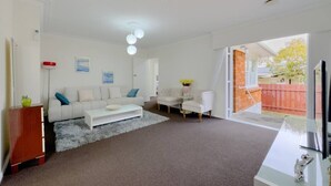 Un salon comprenant un canapé, une table basse et des fauteuils, une cheminée et une vue sur l’extérieur.