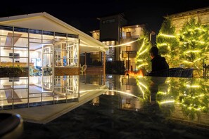 A modern building with a glass facade, outdoor seating, and a well-lit patio area. - Indrasthan himalaya Resort  (Chandragiri)