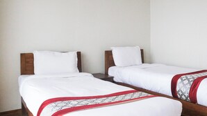 Two single beds with wooden headboards, white bedding, and a patterned red and white throw blanket. - Indrasthan himalaya Resort  (Chandragiri)