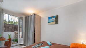 A bedroom with a bed, a desk, and a chair. There is a window with curtains, a painting on the wall, and a view of the outside. - Les Girelles by Interhome (Cannes)