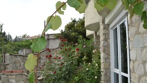 Ein Steinhaus mit einem Fenster und einem Rosengarten.