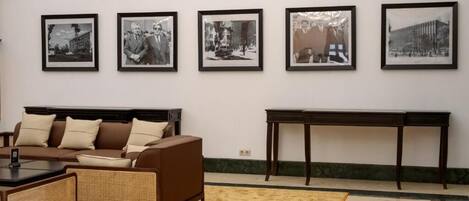 A room with a brown sofa, a small table, and a large framed picture on the wall.