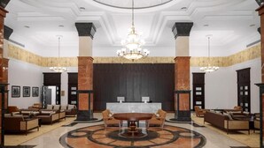 Een hal met een ronde centrale tafel, banken en een receptiebalie.