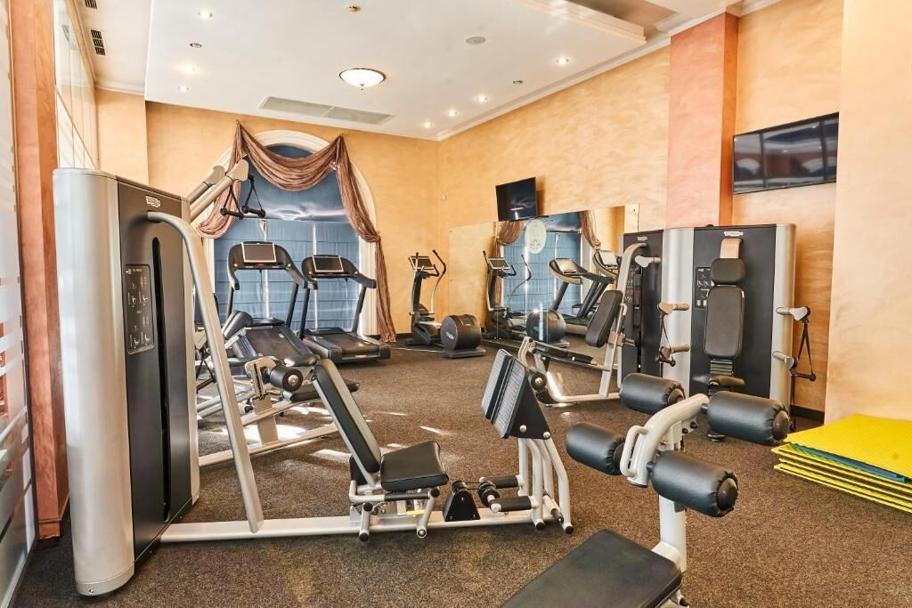 A gym with cardio machines, weight stations, and a mirrored wall.