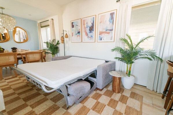 A compact room with a bed, a dining table, chairs, and two potted plants. - 4 Br, Roof Deck, Hot Tub, Steps to Beach & Dining (Newport Beach)