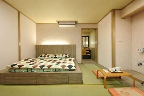 A hotel room with a bed, a small table, a mirror, and a green mat.