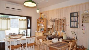 A room with wooden furniture, a dining table, a kitchen area, and a window with curtains. - Jiufen Sunnyrain-bed-and-breakfast (New Taipei City)