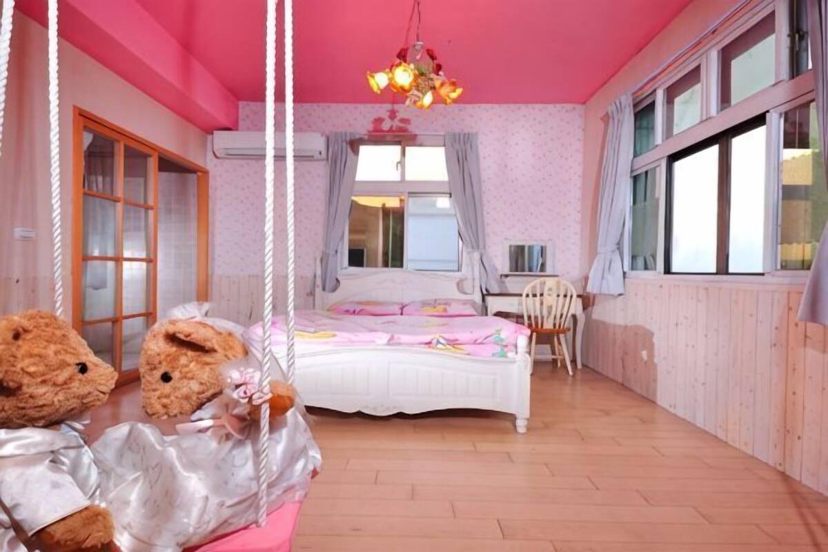 Ein Schlafzimmer mit einem Bett, einem Sessel, einer Schaukel und zwei Teddybären.