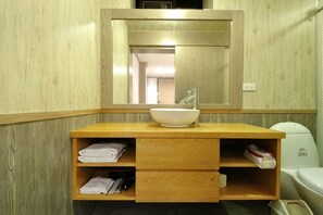 A bathroom with a wooden vanity, a white sink, and a mirror above it.