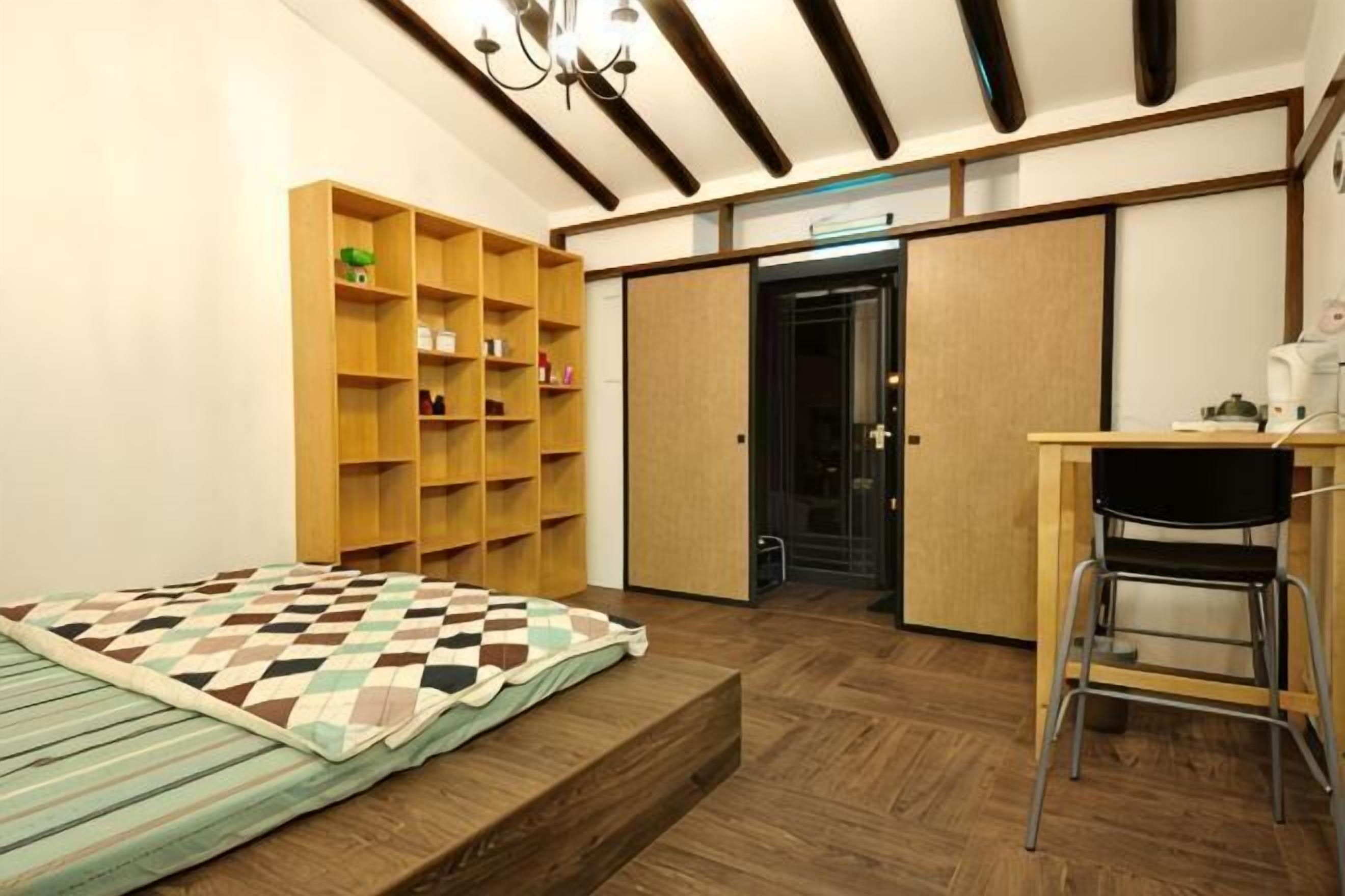Ein Schlafzimmer mit einem Bett, Holzregalen, einem Schreibtisch und einem Stuhl.