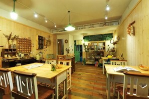 A cozy, well-lit room with wooden walls and floors, featuring a dining table, chairs, and a bookshelf. - Jiufen Sunnyrain-bed-and-breakfast (New Taipei City)