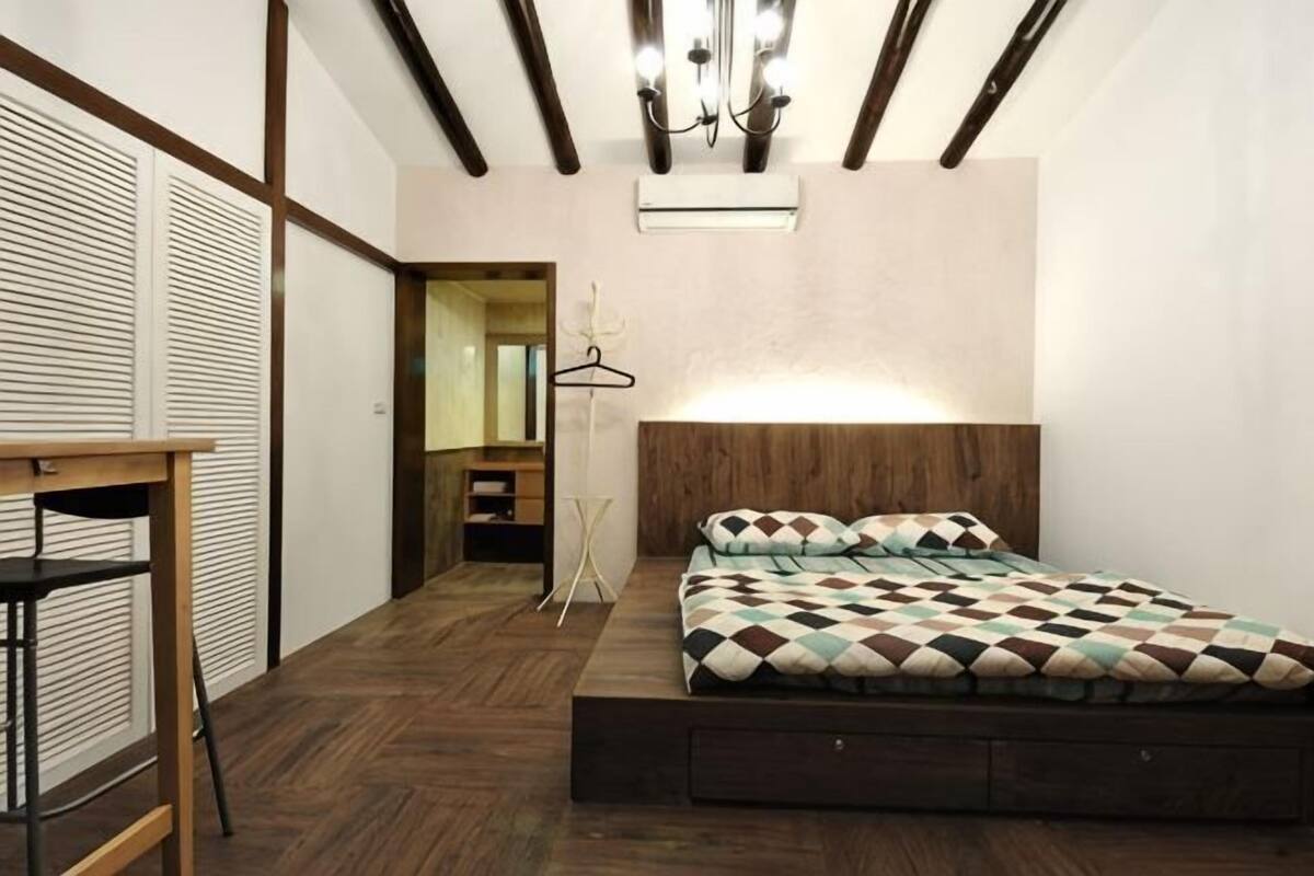 Ein Schlafzimmer mit Bett, Schreibtisch, Pendelleuchte und Kleiderschrank.
