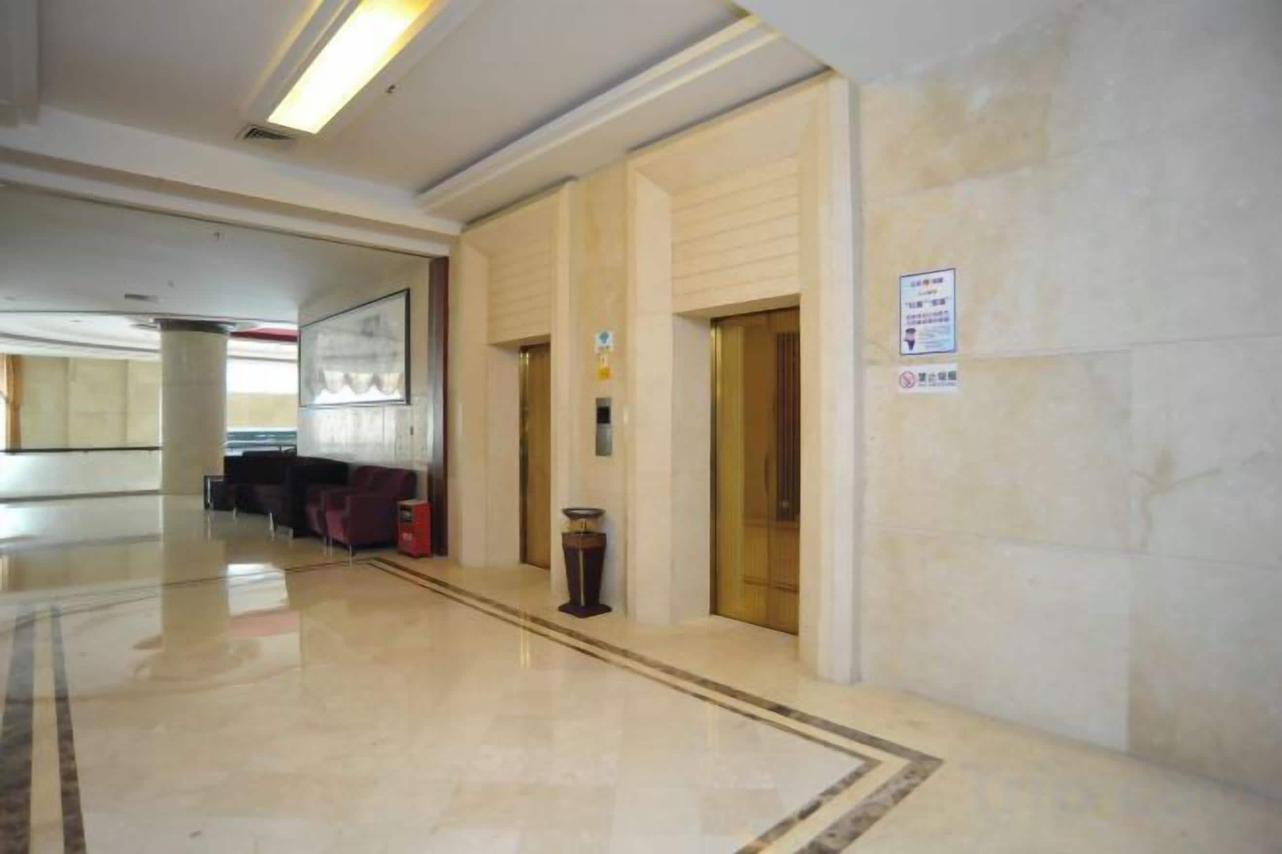 Un hall de hotel con piso de mármol, una recepción y un letrero en la pared.