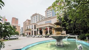 A courtyard with a fountain, surrounded by buildings and parked cars. - Xinghe Hotel(Dongguan Humen road east) (Dongguan)