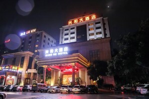 A hotel with a prominent sign, multiple floors, and a parking lot.