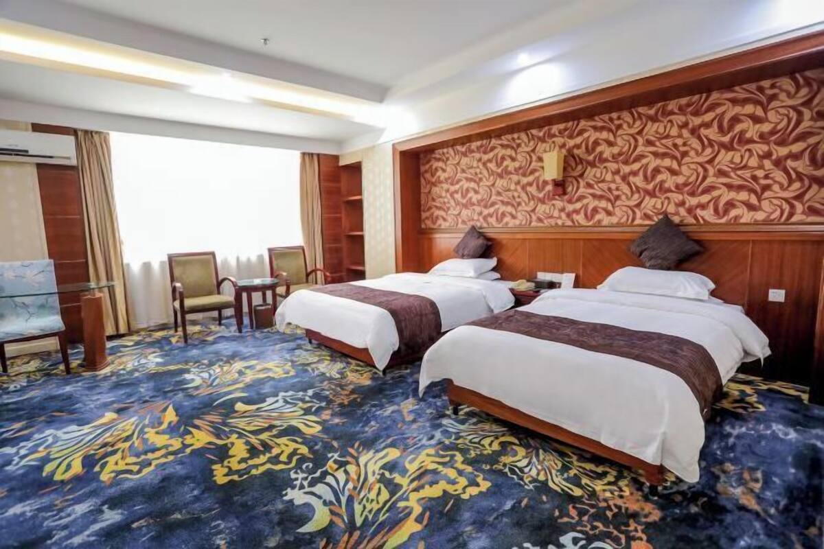 A hotel room with two beds, a desk, and a chair.