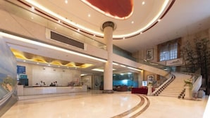 A spacious lobby with a curved reception desk, a staircase, and a large column. - Xinghe Hotel(Dongguan Humen road east) (Dongguan)