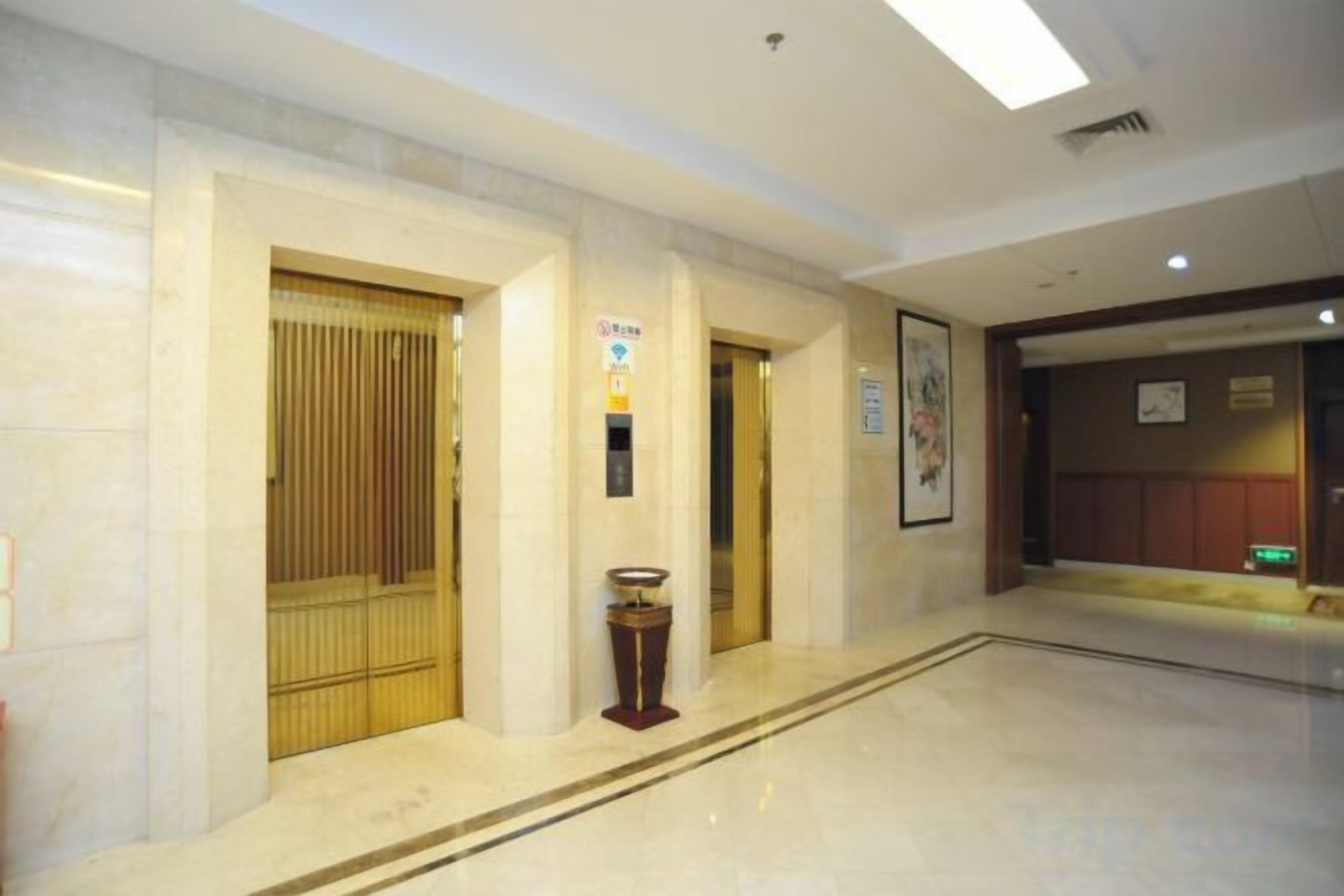 Un vestíbulo de hotel con piso de mármol, una recepción y un reloj en la pared.