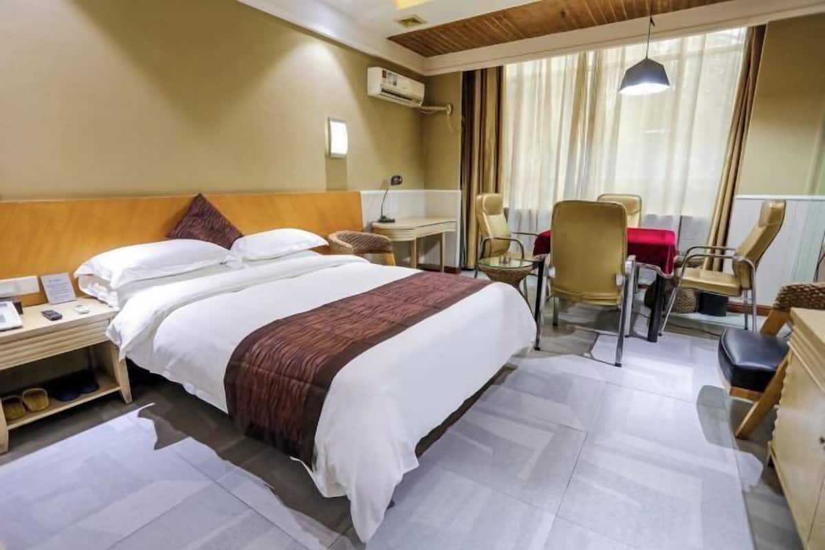 A hotel room with a bed, a desk, a chair, and a window with curtains.