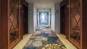 A hotel hallway with a patterned carpet, wooden doors with glass panels, and directional signs. - Xinghe Hotel(Dongguan Humen road east) (Dongguan)