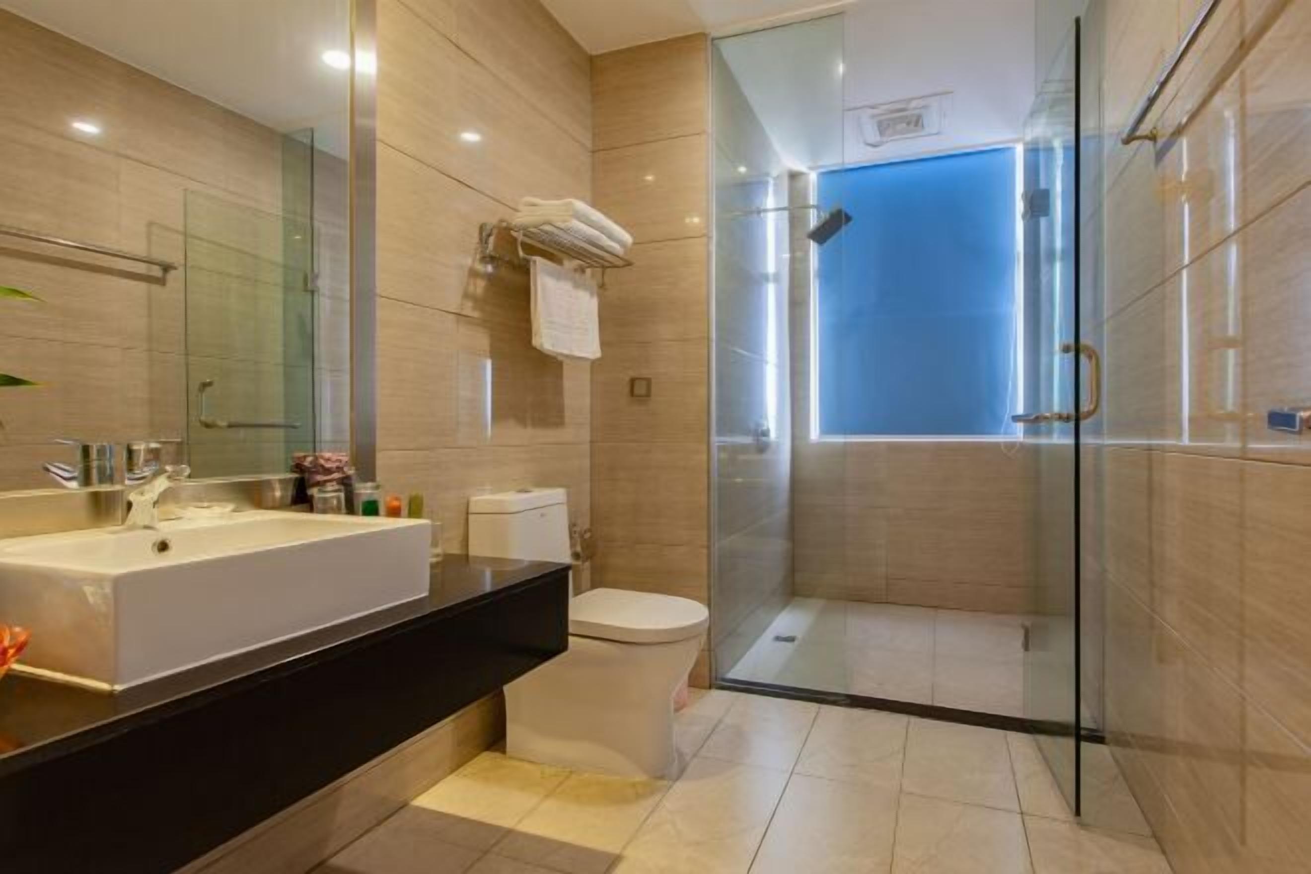 A modern bathroom with a large sink, toilet, and glass-enclosed shower.