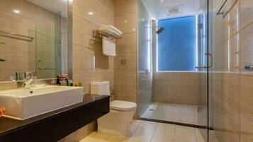 A modern bathroom with a large sink, toilet, and glass-enclosed shower.