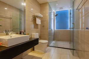 Un baño moderno con un lavamanos grande, inodoro y ducha con mampara de vidrio.