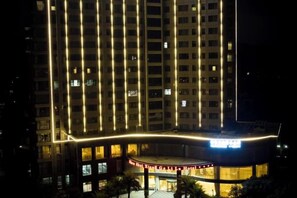 A multi-story hotel with a curved entrance and illuminated windows. - Shan Shui Xiang Ge Li La Hotel (Dingnan)