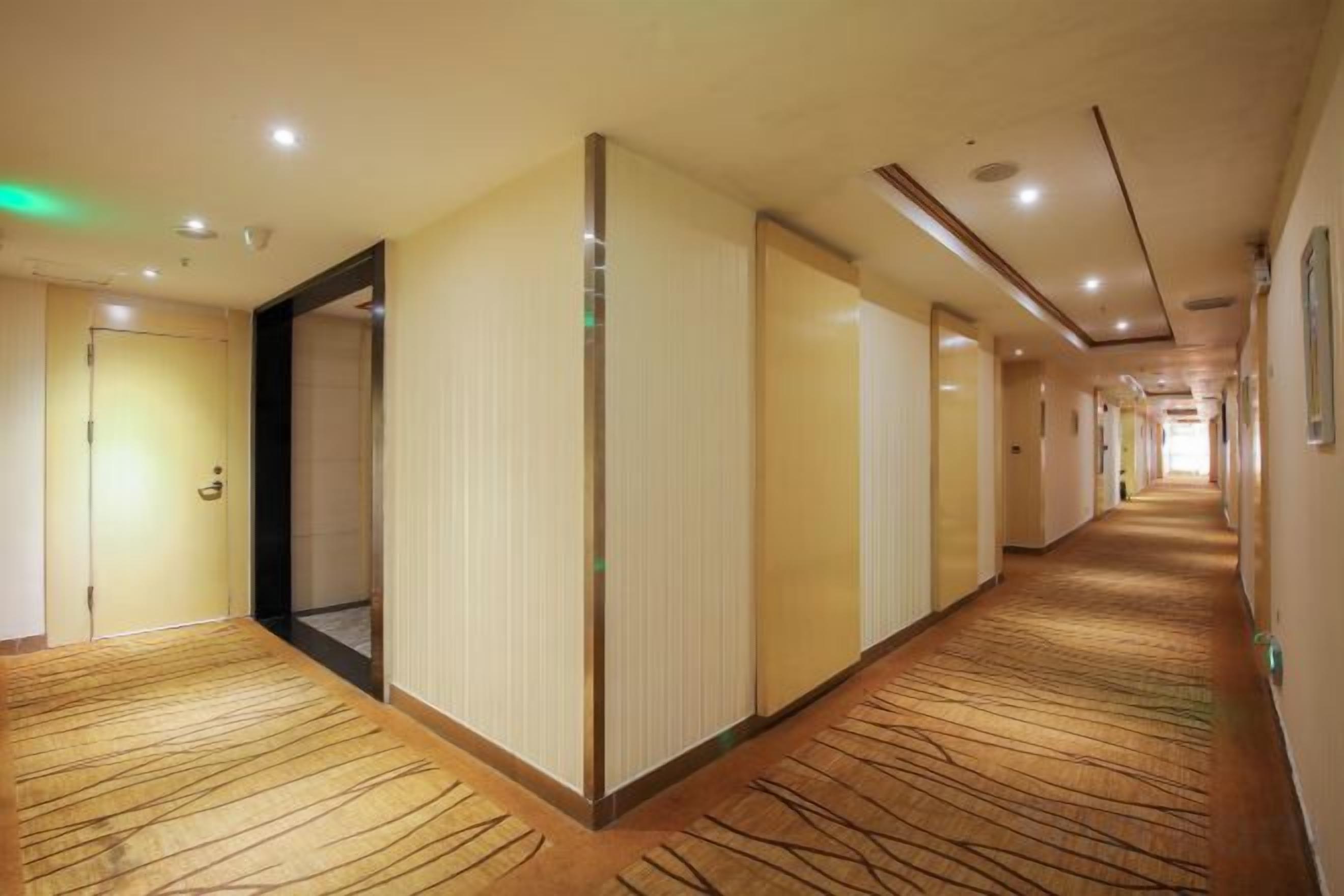 A hotel corridor with carpeted floors, doors, and recessed lighting.