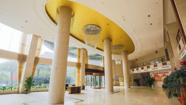 Un hall d’entrée spacieux, doté de hauts plafonds, de grandes colonnes et d’un lustre central.