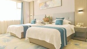 Une chambre d’hôtel avec deux lits, une table de chevet avec un téléphone, une œuvre d’art accrochée au mur et une fenêtre avec des rideaux.