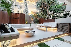 En moderne udendørs terrasse med en sofa, et bord og en skål.