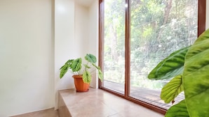 A corner of a room with a potted plant on a windowsill, a large window, and a view of greenery outside. - Areca Boracay Bed & Breakfast (Boracay Island)