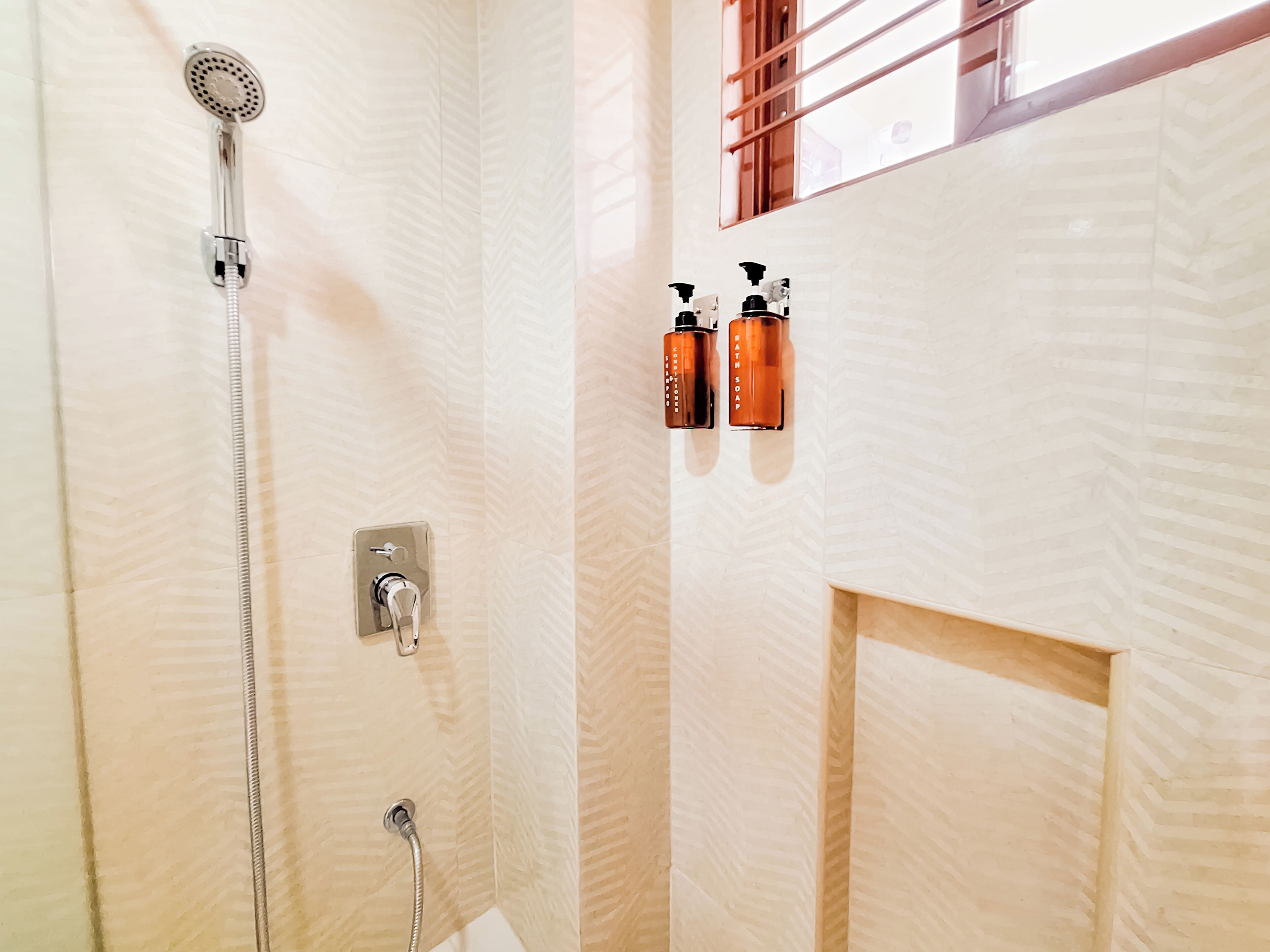 A bathroom with a shower, a towel rack, and a soap dispenser.