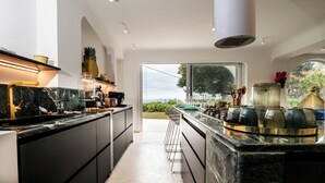 A modern kitchen with a large island, a view of the outdoors, and a minimalist design. - The Sicily Lobster House (naso)