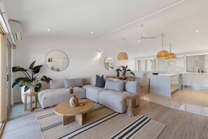Sala de estar moderna com sofá, mesa de centro e área de jantar com ilha de cozinha.
