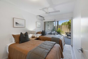 A hotel room with two beds, a ceiling fan, a window with a view of the outdoors, and a door leading to a balcony. - Riverfront Luxury - Poolside, Near Hastings (Noosa)