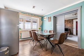 Un comedor con una mesa y sillas, un refrigerador, y vistas de la habitación contigua.