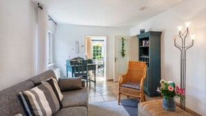 A living room with a sofa, chair, dining table, and a bookshelf. - Apartment 'Haus Ute' with Private Terrace, Private Garden and Wi-Fi (Arnsberg)