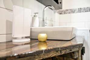 Un baño con un lavamanos blanco, un grifo moderno y una encimera de madera.
